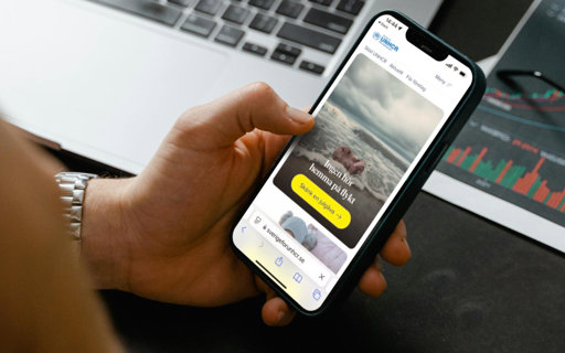 Hand som håller i en telefon med hemsidan Sverige för UNHCR