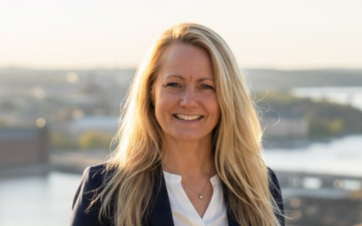 Lisa står med utsläppt långt blont hår på en grusväg med träd i bakgrunden