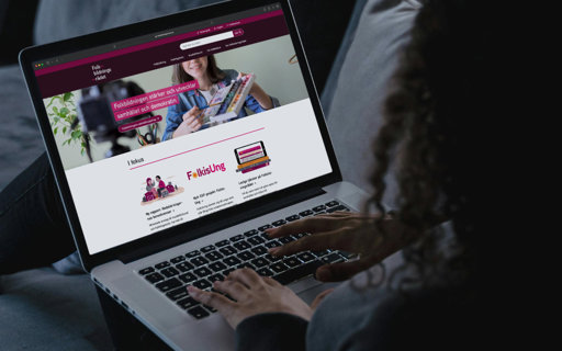 Person använder laptop som visar Folkbildningsrådets webbplats med rubriken ’Folkbildningen stärker och utvecklar samhället och demokratin'.