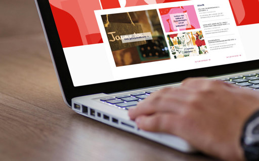 Närbild på händer som använder laptop med Munskänkarnas webbsida öppen, som visar artiklar och nyheter om vin.